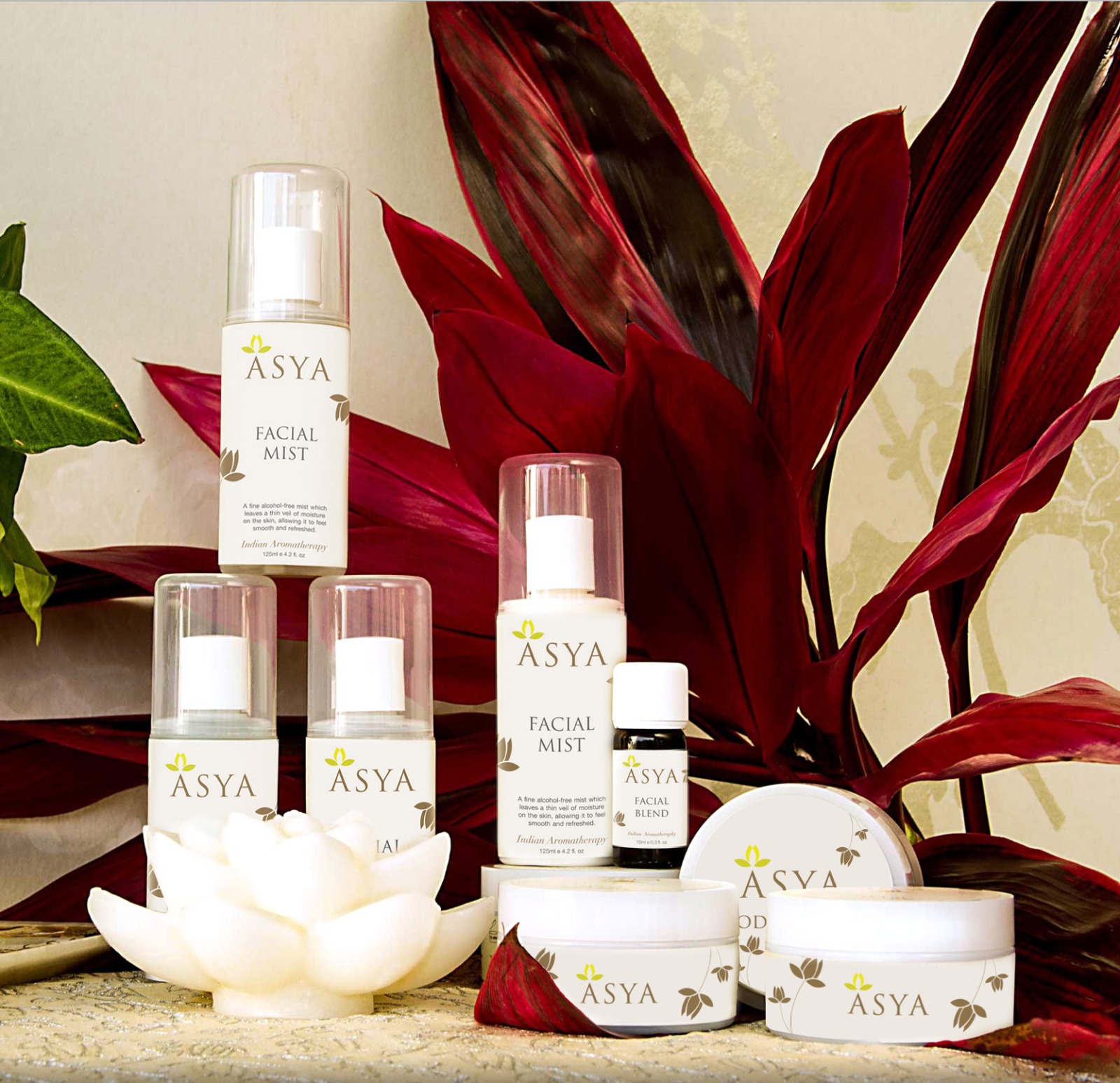 Asya wellness range styled with deep red foliage and a lotus candle