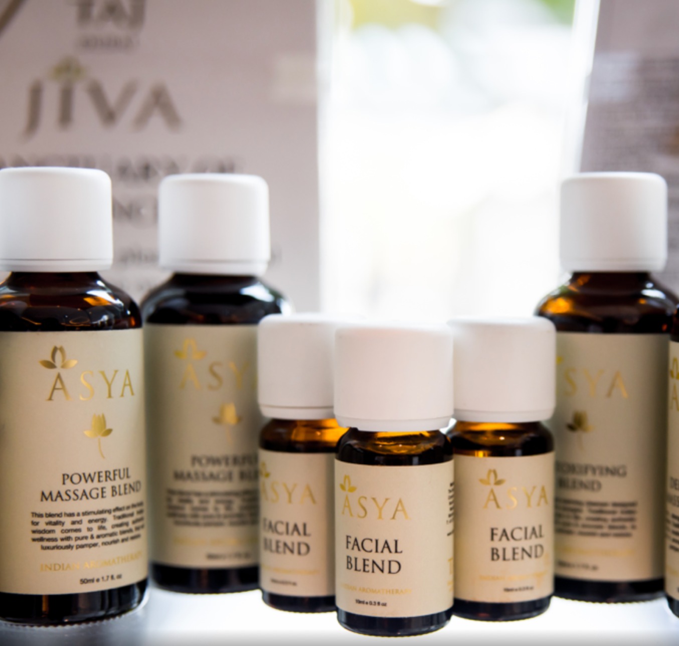 Asya amber bottles lined up: massage and facial blends with gold lotus labels